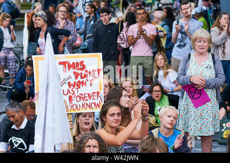 La Ribellione di estinzione il cambiamento climatico manifestanti ascolto di interventi al di fuori del Municipio sul London South Bank, il 18 Luglio 2019 Foto Stock