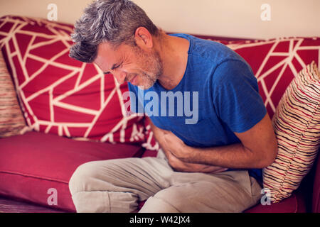 L'uomo sente forte dolore allo stomaco a casa. La gente, la sanità e la medicina concept Foto Stock