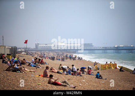 La gente continua a godere del sole nonostante i forti venti sulla spiaggia di Brighton in East Sussex.Mercoledì 20 Luglio 2016. Foto Stock