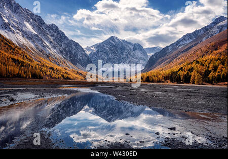 La straordinaria riflessione del picco di Karatash e nubi in un piccolo ruscello. Aktru. Montagne di Altai. La Siberia. La Russia. Il focus principale sul picco di carati Foto Stock
