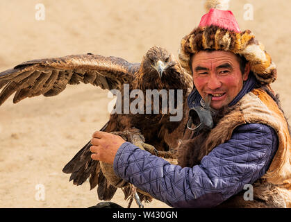 Bayan-Ulgii, Mongolia occidentale - Ottobre 07, 2018: Giochi nomade, Golden Eagle Festival. Giornata di sole. Il cacciatore mongolo è seduto con Golden Eagle a portata di mano Foto Stock