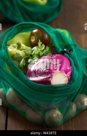 Nessun sacchetto di plastica del concetto. Borse di maglia di un assortimento di verdure su un tavolo di legno Foto Stock