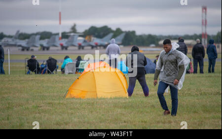 RAF Fairford, Glos, Regno Unito. Il 19 luglio 2019. Giorno 1 del Royal International Air Tattoo (RIAT) con velivoli militari provenienti da tutto il mondo per assemblaggio di più grande del mondo che airshow corre da 19-21 luglio. Giorno 1 battenti display è fortemente ridotta a causa della bassa base cloud, forte pioggia e vento. Immagine: linea di visitatori la pista sotto cieli grigi per battenti visualizza. Credito: Malcolm Park/Alamy Live News. Foto Stock
