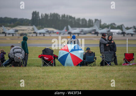 RAF Fairford, Glos, Regno Unito. Il 19 luglio 2019. Giorno 1 del Royal International Air Tattoo (RIAT) con velivoli militari provenienti da tutto il mondo per assemblaggio di più grande del mondo che airshow corre da 19-21 luglio. Giorno 1 battenti display è fortemente ridotta a causa della bassa base cloud, forte pioggia e vento. Immagine: linea di visitatori la pista sotto cieli grigi per battenti visualizza. Credito: Malcolm Park/Alamy Live News. Foto Stock