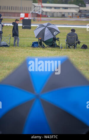 RAF Fairford, Glos, Regno Unito. Il 19 luglio 2019. Giorno 1 del Royal International Air Tattoo (RIAT) con velivoli militari provenienti da tutto il mondo per assemblaggio di più grande del mondo che airshow corre da 19-21 luglio. Giorno 1 battenti display è fortemente ridotta a causa della bassa base cloud, forte pioggia e vento. Immagine: linea di visitatori la pista sotto cieli grigi per battenti visualizza. Credito: Malcolm Park/Alamy Live News. Foto Stock