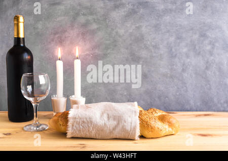 Lo shabbat o Shabath concetto. Challah pane e vino di shabbat, libro e candele su tavola, copia dello spazio. Tradizionale ebraica rito di Shabbat. Foto Stock