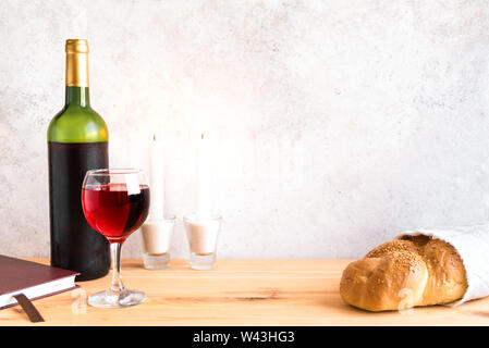 Lo shabbat o Shabath concetto. Challah pane e vino di shabbat, libro e candele su tavola, copia dello spazio. Tradizionale ebraica rito di Shabbat. Foto Stock