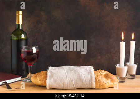 Lo shabbat o Shabath concetto. Challah pane e vino di shabbat, libro e candele su tavola, copia dello spazio. Tradizionale ebraica rito di Shabbat. Foto Stock