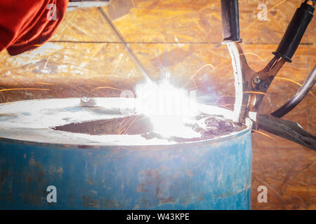 Lavoratore con Red Glove per proteggere la scintilla di luce con processo di saldatura con tubo blu metallico e luminose scintille in acciaio Foto Stock