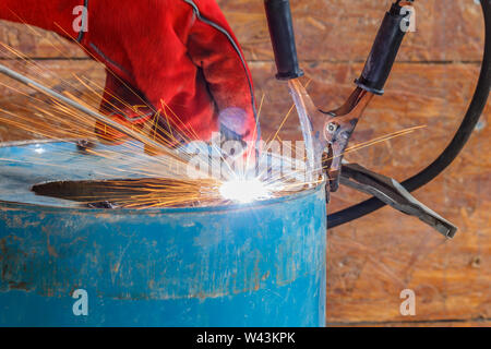 Lavoratore con Red Glove per proteggere la scintilla di luce con processo di saldatura con tubo blu metallico e luminose scintille in acciaio Foto Stock