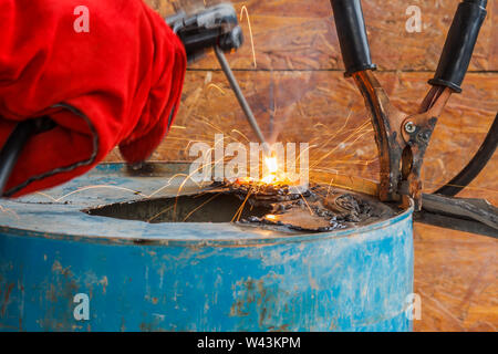 Lavoratore con Red Glove per proteggere la scintilla di luce con processo di saldatura con tubo blu metallico e luminose scintille in acciaio Foto Stock