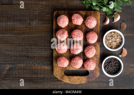 Materie le polpette di carne e spezie sullo sfondo di legno, vista dall'alto Foto Stock