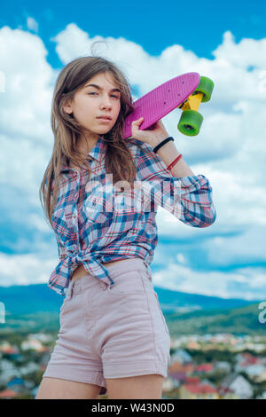 Mini in plastica cruiser board. Molla. Scena urbana, la vita della città. skateboard sport hobby. Attività estiva. pronto per la corsa su strada. Hipster ragazza con pe Foto Stock