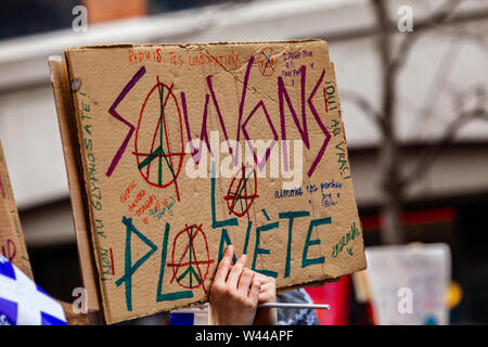 Un segno francese è visto closeup durante un rally ambientale, dicendo a salvare il pianeta e raffiguranti il simbolo della pace, come i manifestanti marzo in una strada della citta'. Foto Stock