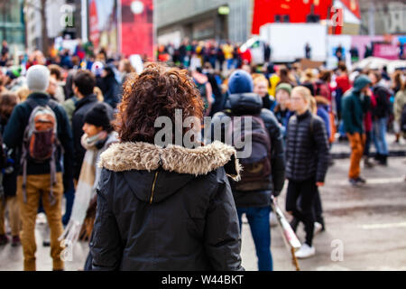 Una giovane donna con i capelli ricci è visto closeup da dietro un eco-friendly la protesta è visto sfocata in background, con spazio di copia Foto Stock