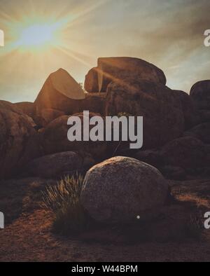 Scatto verticale di una roccia con il sole che splende dentro il cielo Foto Stock