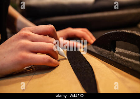 Le mani di un lavoratore di moda sono visti da vicino all'interno di un workshop. Creazione di eco-friendly vestiti a mano. Esperto in lavoro. Foto Stock