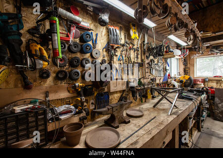 Una varietà di lamiera utensili abrasivi compresi dischi di taglio per appendere su un banco di lavoro all'interno di un garage. Utili strumenti ben organizzato al di sopra di una workstation. Foto Stock