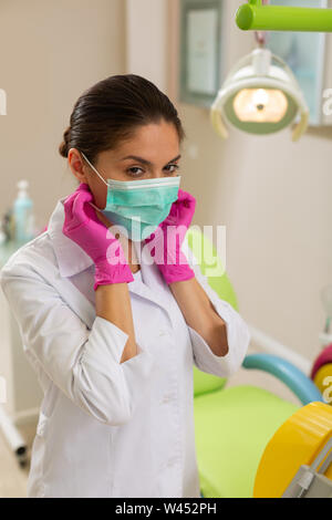 Dentista in un camice e guanti asettici Foto Stock