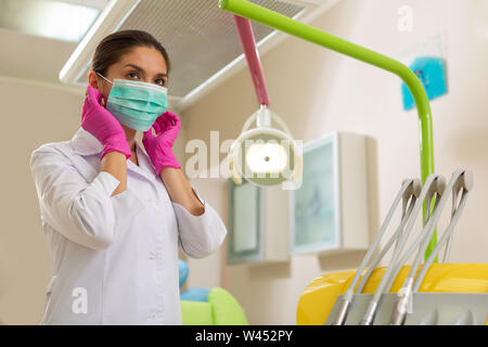 Medico che indossa una maschera verde e guanti asettici Foto Stock