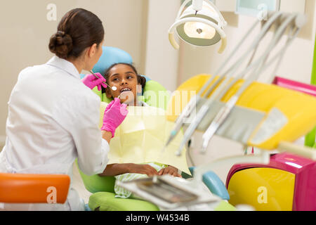 Ragazza giovane e carina tranquillamente seduto nella sedia dentisti Foto Stock
