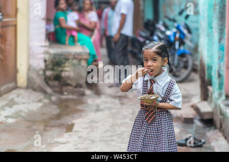 Una bambina idli mangiare per colazione prima della scuola di Varanasi (India). Foto Stock