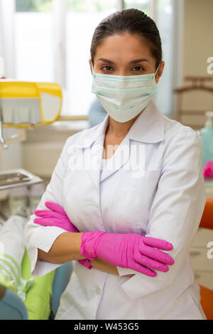 Medico con le braccia incrociate in uno studio dentistico Foto Stock