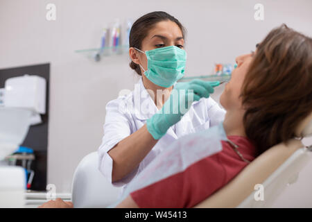 Dentista seduto di fronte a lei paziente di sesso maschile Foto Stock