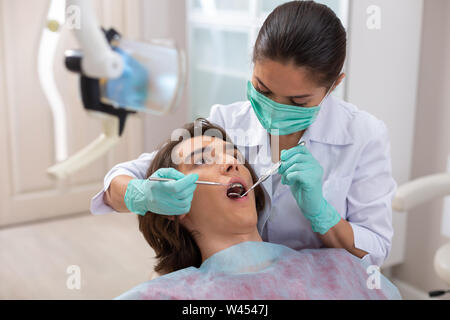 Dentista femmina cercando in pazienti maschi in bocca Foto Stock