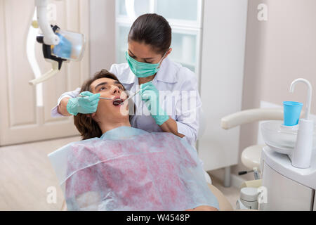 Concentrato grave medico donna in una maschera di verde Foto Stock