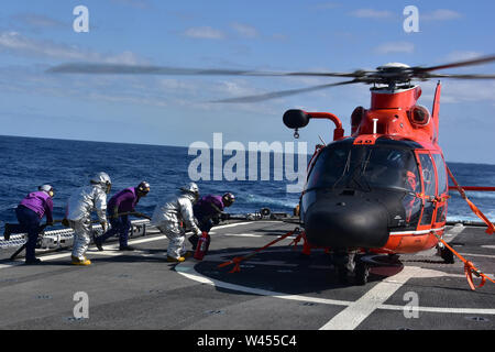 Oceano Pacifico-il suo equipaggio dalla U.S. Guardacoste Bertholf condotta "a caldo" di carburazione - refuellng un aeromobile mentre i suoi motori sono in esecuzione -- dell'equipaggio imbarcato MH-65 Delfino elicottero 6 febbraio 2019. Bertholf è su un mese-lungo la distribuzione per l'Oceano Pacifico occidentale a sostegno dell'U.S. Marina 7 della flotta. Stati Uniti Coast Guard foto di Chief Petty Officer John Masson. Foto Stock