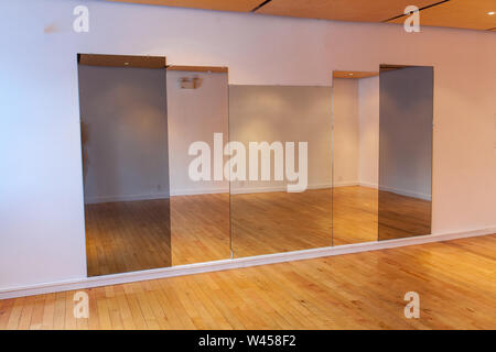 Alti specchi sono vedere appeso all'interno di una camera deserta. Edificio di ricreazione con camera disponibile a noleggio, ampio spazio per la danza di truppa ginnasta o pratica Foto Stock