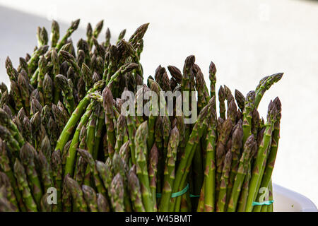 Fasci di Erba Sparrow (Asparagus officinalis) vengono visti da vicino. Fresche verdure verdi venduti a un allevamento all'aperto sul mercato. Copia spazio verso l'alto. Foto Stock