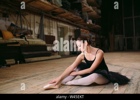 Giovane ballerina in abito nero treni dietro le quinte. Foto Stock