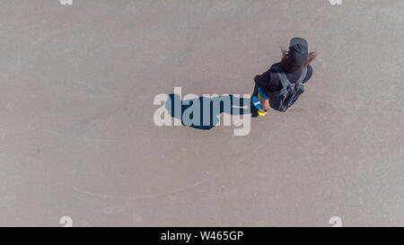 Guy rides uno skateboard, vista dall'alto, l'ombra sul marciapiede. Lo stile di vita della gioventù, copia spazio sulla sinistra Foto Stock