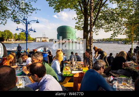 Amsterdam, Paesi Bassi, Boom Hannekes beer garden sul lungomare con una vista del Museo di Nemo, Foto Stock