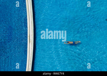 Vista dall'alto di uomo felice è rilassante e godervi una nuotata nella piscina del lussuoso hotel e resort con la calda luce del sole bellissimo al summertim Foto Stock