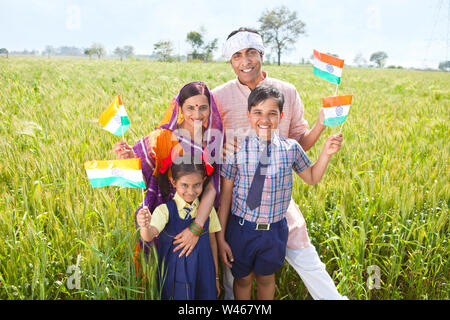 Famiglia rurale che tiene bandiera e sorridente Foto Stock