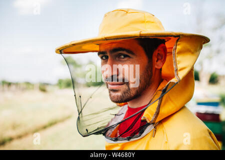 Ritratto di un apicoltore in un giallo tuta di protezione lavora su un apiario Foto Stock