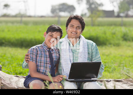 Ritratto di un uomo che usa un computer portatile con suo figlio Foto Stock