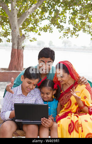Famiglia rurale che utilizza un computer portatile Foto Stock