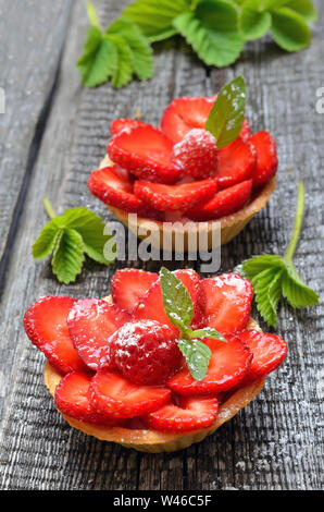 Tortine con fragole fresche sul tavolo di legno Foto Stock