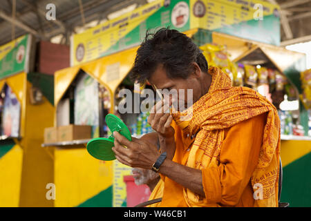 Sadhu applicando tika sulla sua fronte in corrispondenza di una piattaforma Foto Stock