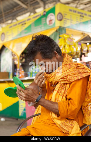 Sadhu applicando tika sulla sua fronte in corrispondenza di una piattaforma Foto Stock