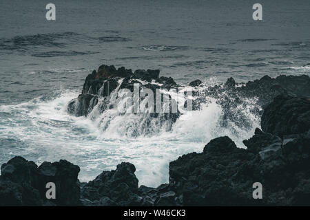Azzorre, grandi onde che si infrangono sulla roccia vulcanica nera sull'Oceano Atlantico sulla costa dell'isola di Sao Miguel nelle Azzorre, Portogallo Foto Stock
