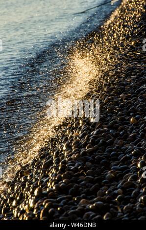 Forme d'onda colpendo round rocce e schizzi Foto Stock