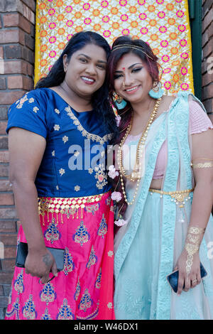 Due belle donne Indù attendono gli arrivi dello sposo e della sposa prima di un tradizionale matrimonio induista in Ozone Park, Queens, a New York City. Foto Stock