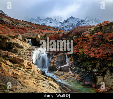 Una piccola cascata di fronte Fitzroy mountain range. Colori d'Autunno nel parco nazionale Los Glaciares. El Chalten. Nasello di Patagonia Argentina. Andes Foto Stock