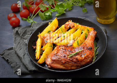 Pollo alla griglia della gamba con erbe e patate fritte in padella Foto Stock