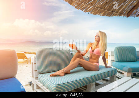 Donna che mantiene una deliziosa classic iced aperol spritz cocktail con cubetti di ghiaccio su una calda spiaggia tropicale in estate sole Foto Stock